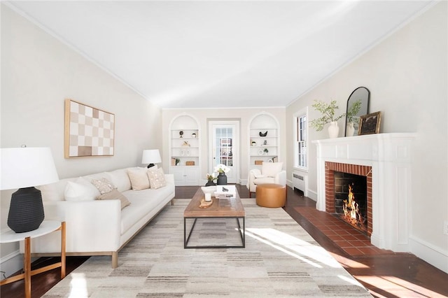 living area featuring lofted ceiling, a fireplace, wood finished floors, built in features, and radiator heating unit