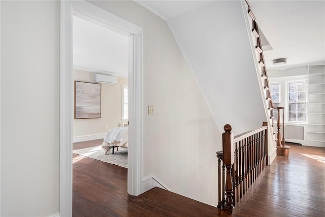 hall featuring hardwood / wood-style flooring, a wealth of natural light, an AC wall unit, and an upstairs landing