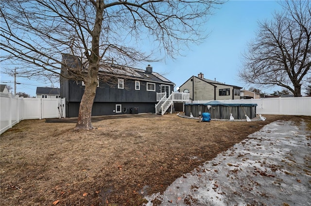 back of house featuring a fenced backyard, a fenced in pool, and a yard