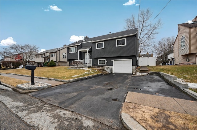 bi-level home featuring an attached garage, driveway, a residential view, a chimney, and a front yard