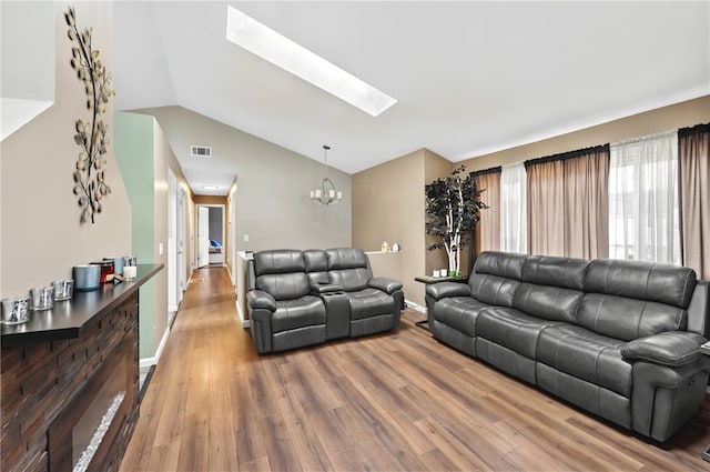 living area with lofted ceiling with skylight, visible vents, a notable chandelier, and wood finished floors