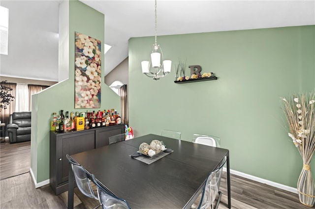 dining room with vaulted ceiling, dark wood-type flooring, a chandelier, and baseboards