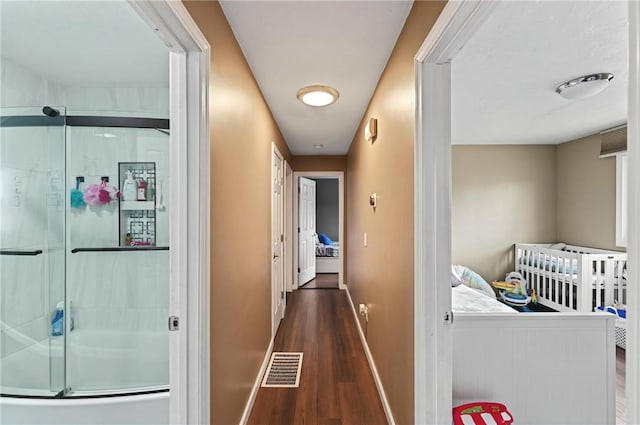 corridor with wood finished floors, visible vents, and baseboards