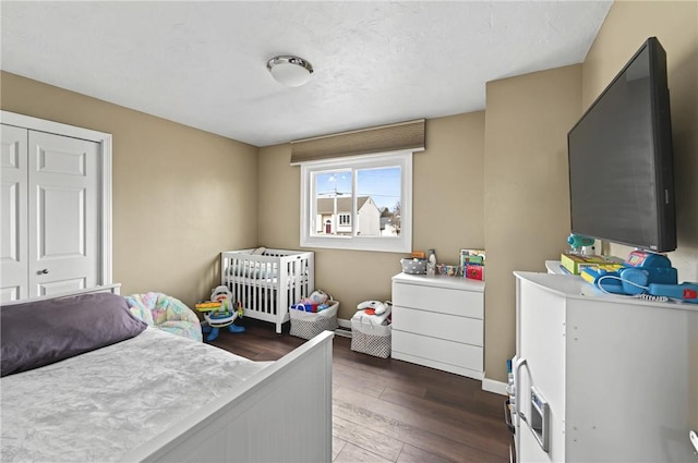 bedroom with dark wood-type flooring, a closet, and baseboards