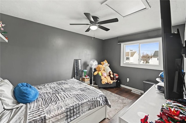 bedroom featuring wood finished floors, a ceiling fan, baseboards, radiator, and attic access