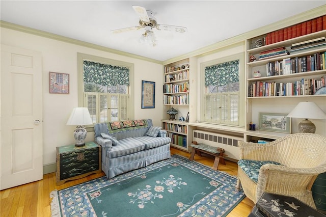 sitting room with crown molding, wood finished floors, a ceiling fan, and radiator