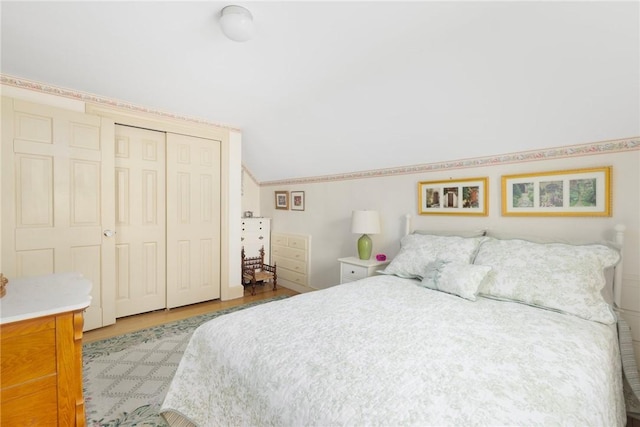 bedroom with a closet, vaulted ceiling, and wood finished floors