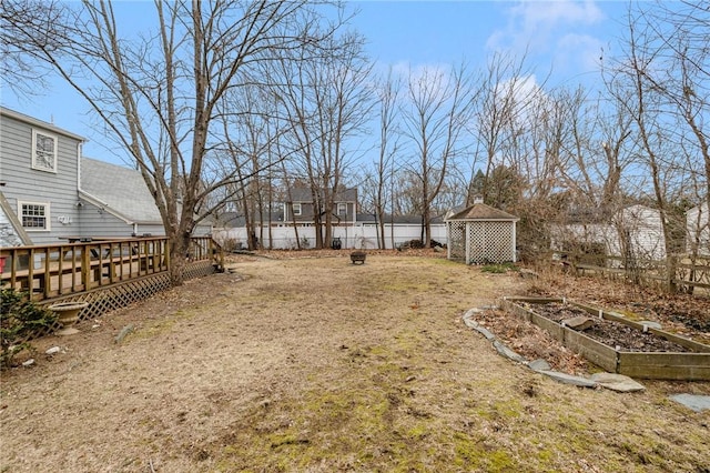 view of yard featuring a deck, an outbuilding, a fenced backyard, and a garden