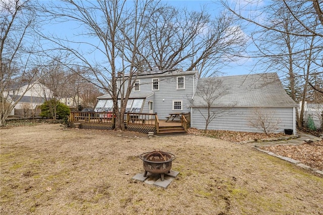 rear view of property featuring a deck, an outdoor fire pit, and a lawn