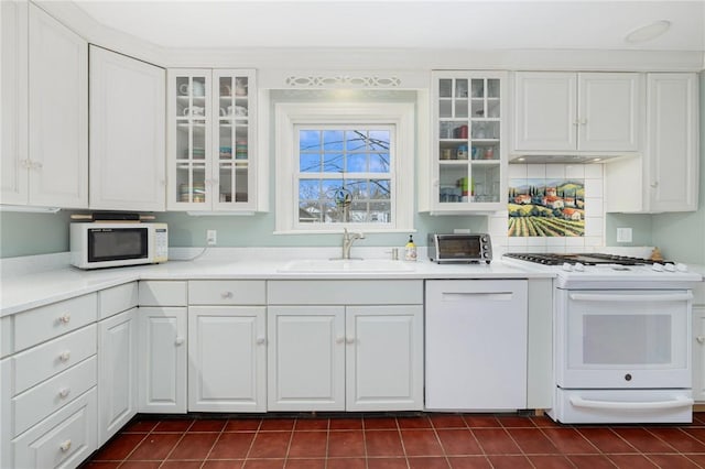 kitchen featuring white appliances, a sink, and white cabinetry