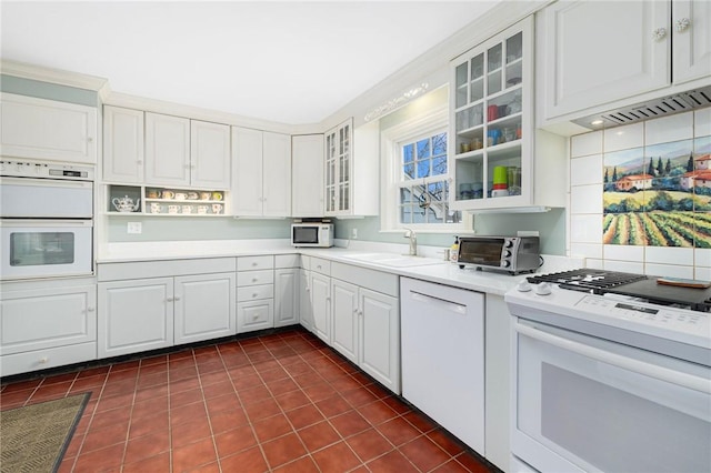 kitchen featuring white appliances, a toaster, white cabinets, light countertops, and a sink