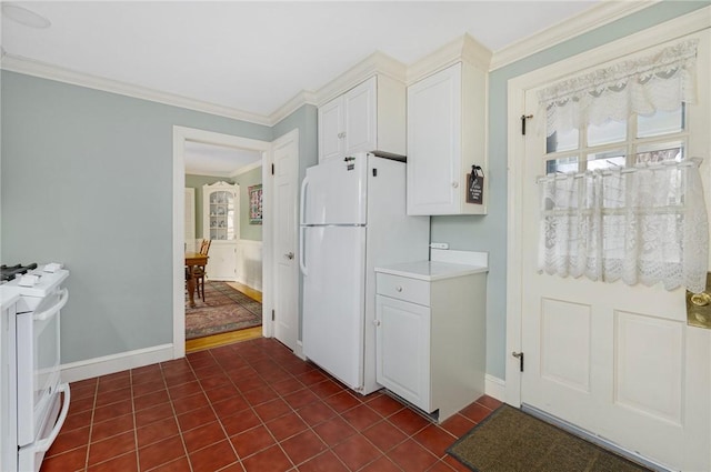 kitchen featuring white appliances, baseboards, white cabinets, ornamental molding, and dark tile patterned floors