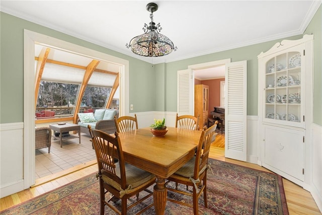 dining room featuring crown molding, wainscoting, and light wood-style floors