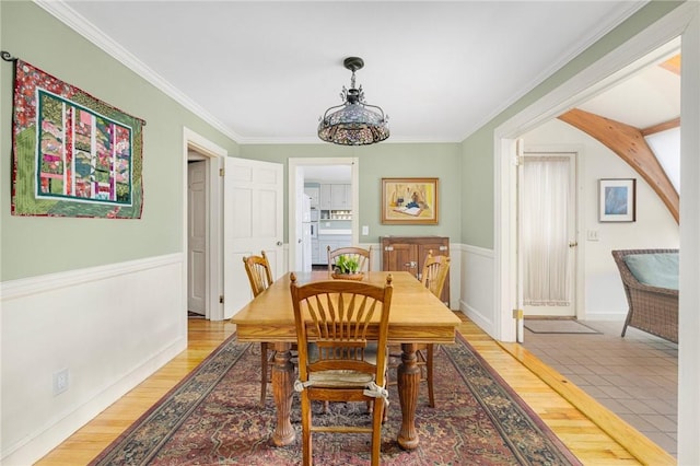 dining area with ornamental molding and light wood-style flooring