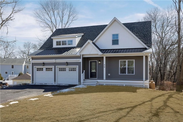 view of front of home with aphalt driveway, roof with shingles, a front yard, a standing seam roof, and metal roof