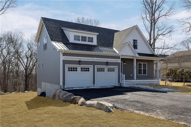 view of front of house featuring metal roof, aphalt driveway, a garage, a front lawn, and a standing seam roof