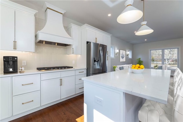 kitchen featuring stainless steel appliances, white cabinets, custom range hood, and decorative backsplash