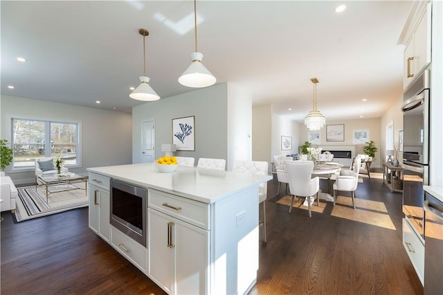 kitchen featuring stainless steel appliances, open floor plan, dark wood-type flooring, and white cabinets