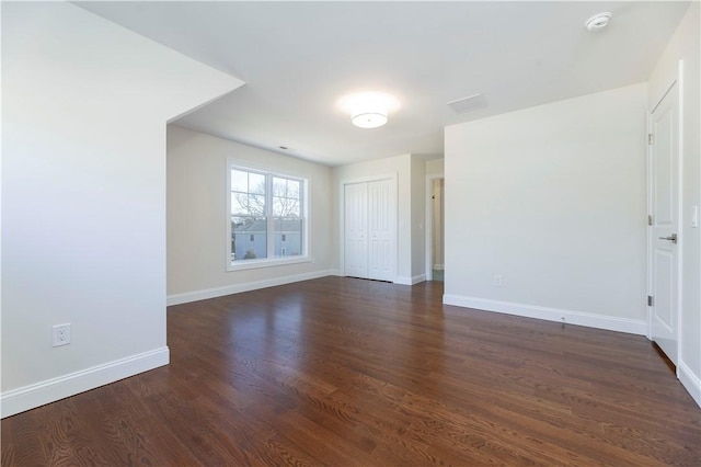 empty room with baseboards and dark wood finished floors