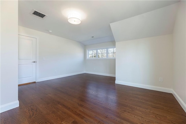 unfurnished room with dark wood-style flooring, visible vents, and baseboards