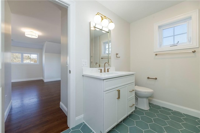 bathroom with baseboards, vanity, and toilet