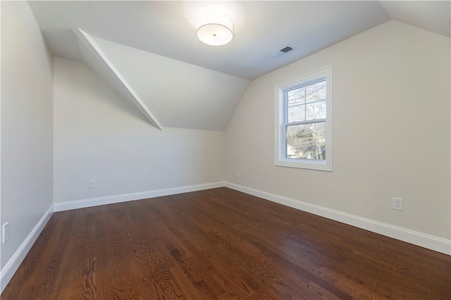 bonus room featuring dark wood-style flooring, visible vents, vaulted ceiling, and baseboards