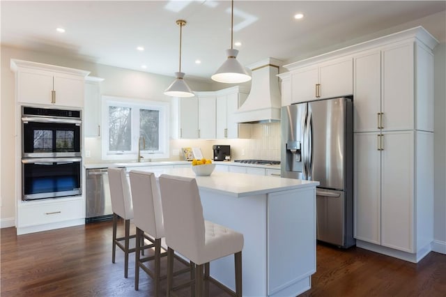 kitchen with a center island, stainless steel appliances, tasteful backsplash, a sink, and premium range hood