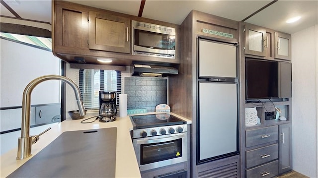 kitchen featuring stainless steel appliances, light countertops, a sink, and tasteful backsplash