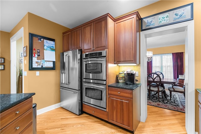 kitchen with baseboards, appliances with stainless steel finishes, brown cabinetry, and light wood-style floors