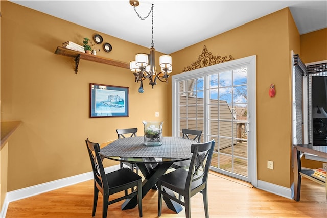 dining room featuring light wood-type flooring, a notable chandelier, and baseboards