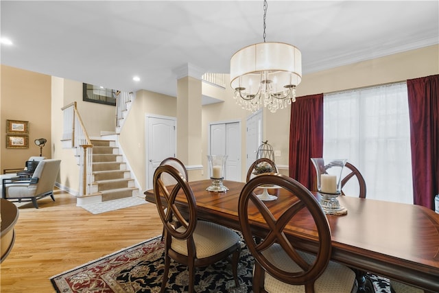 dining space with a notable chandelier, light wood finished floors, ornamental molding, baseboards, and stairs