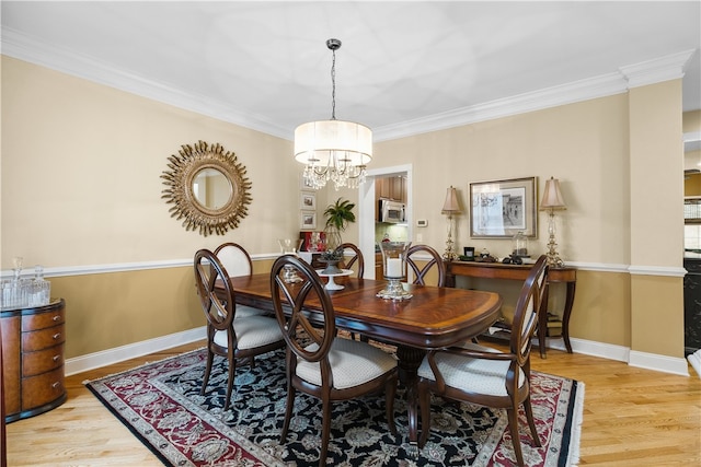 dining area with baseboards, a notable chandelier, light wood-style flooring, and crown molding