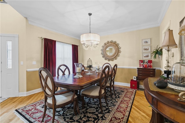 dining space with crown molding, light wood-style flooring, baseboards, and an inviting chandelier