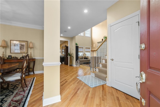 entryway featuring light wood finished floors, baseboards, stairway, crown molding, and recessed lighting