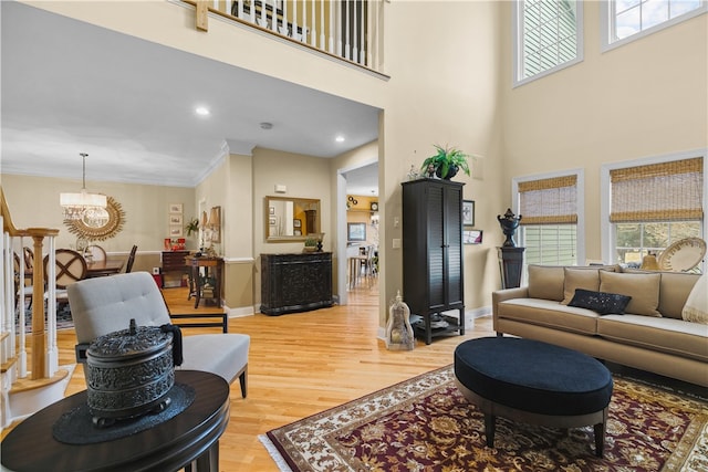 living room with baseboards, a high ceiling, light wood-type flooring, and crown molding