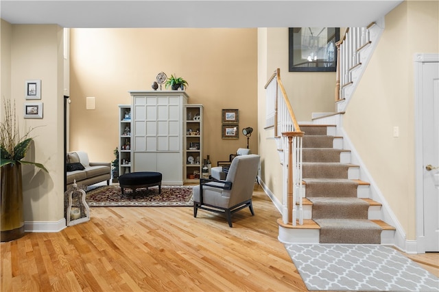 living area featuring light wood-type flooring, stairway, and baseboards