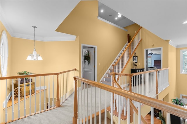 hallway with crown molding, carpet floors, an upstairs landing, and a notable chandelier