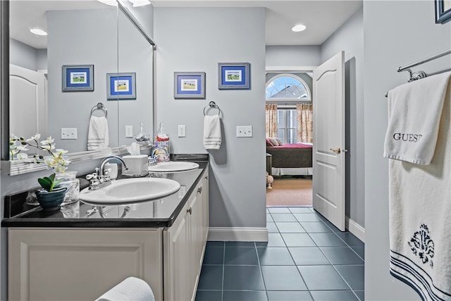 full bath with ensuite bathroom, double vanity, tile patterned flooring, and a sink