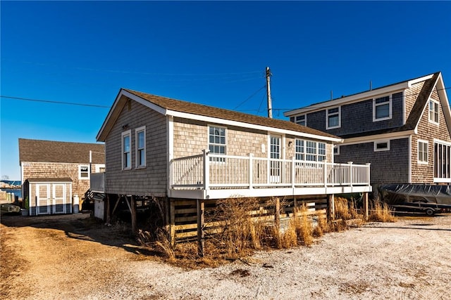 back of property featuring roof with shingles and a wooden deck