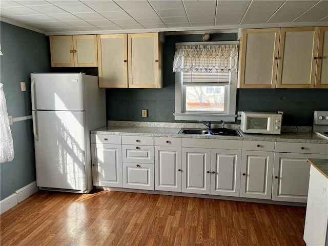 kitchen with light wood-type flooring, white appliances, a sink, and baseboards