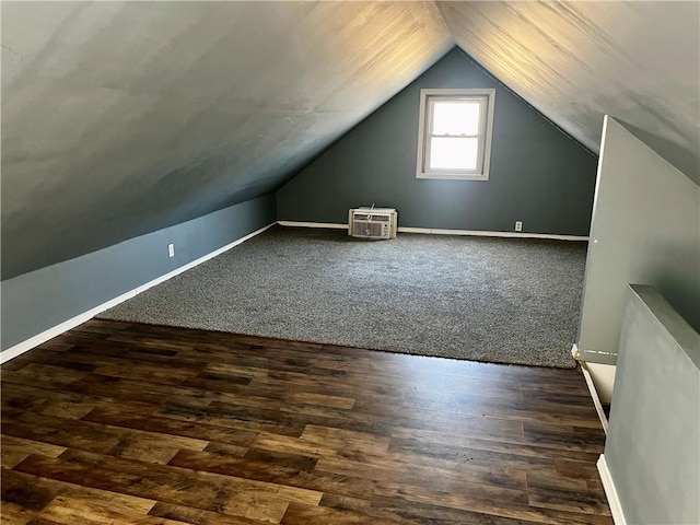 additional living space featuring dark wood-style flooring, vaulted ceiling, and baseboards