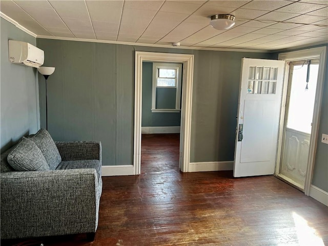 foyer featuring a wall unit AC, baseboards, ornamental molding, and wood finished floors