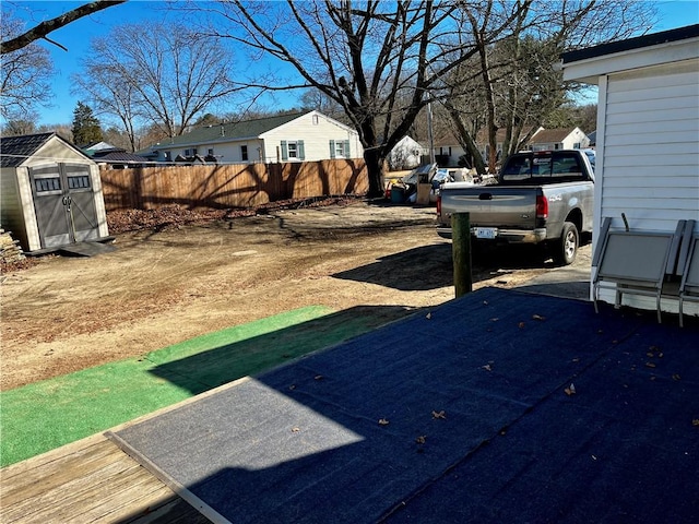 view of yard featuring an outbuilding, a storage unit, fence, and a residential view