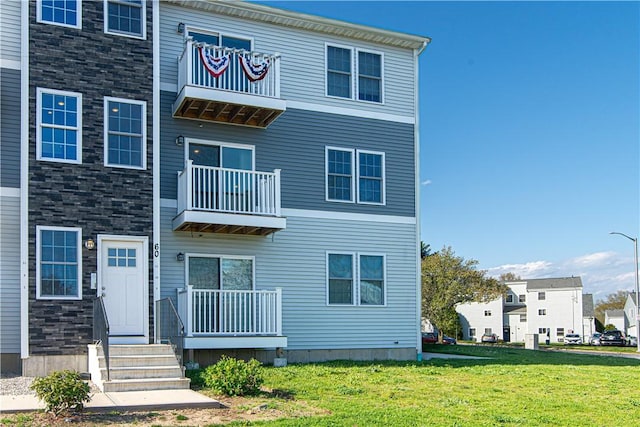 view of front of property featuring a front lawn and a balcony