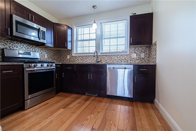 kitchen featuring dark brown cabinetry, light wood finished floors, tasteful backsplash, stainless steel appliances, and a sink