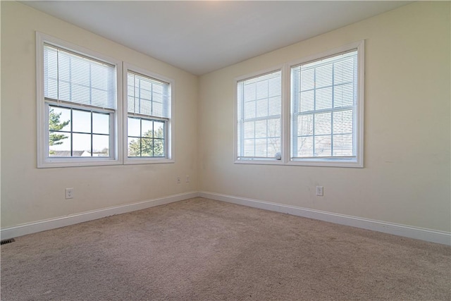 empty room with carpet flooring, visible vents, and baseboards