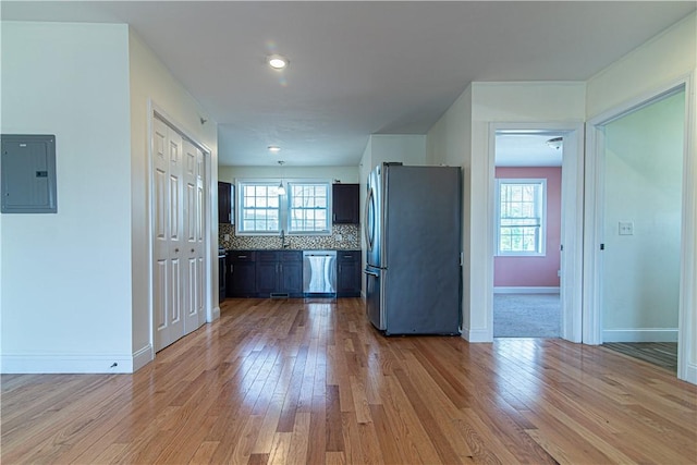 kitchen featuring stainless steel appliances, a sink, backsplash, a wealth of natural light, and electric panel