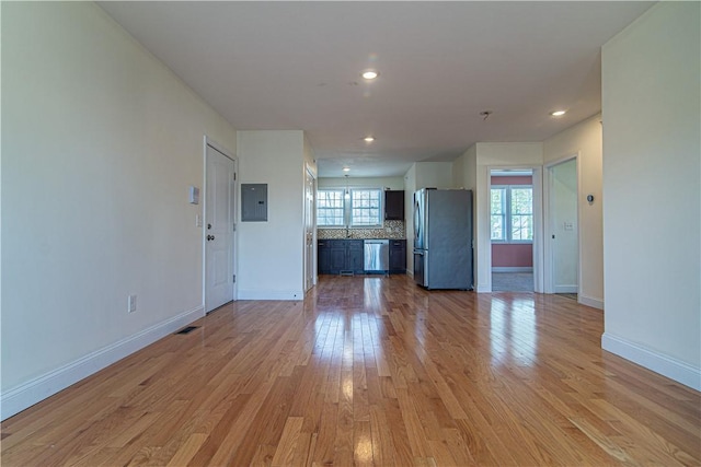 unfurnished living room with light wood-style flooring, recessed lighting, visible vents, baseboards, and electric panel