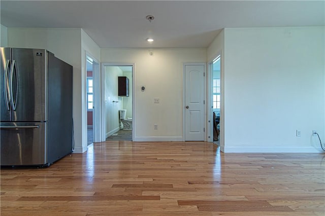 kitchen featuring light wood finished floors, baseboards, and freestanding refrigerator