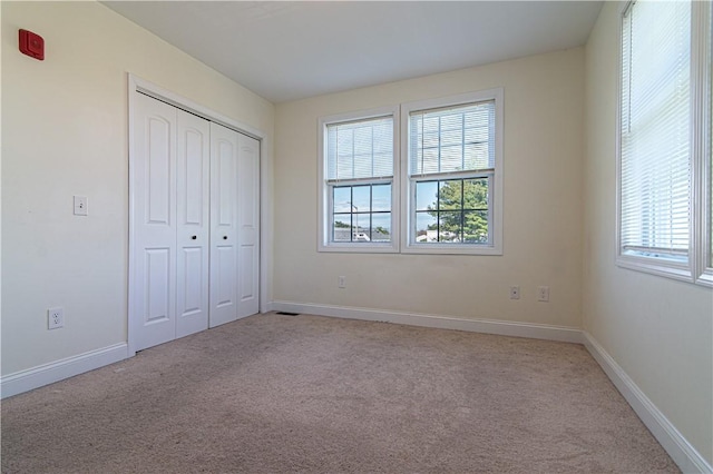 unfurnished bedroom featuring carpet floors, baseboards, and a closet